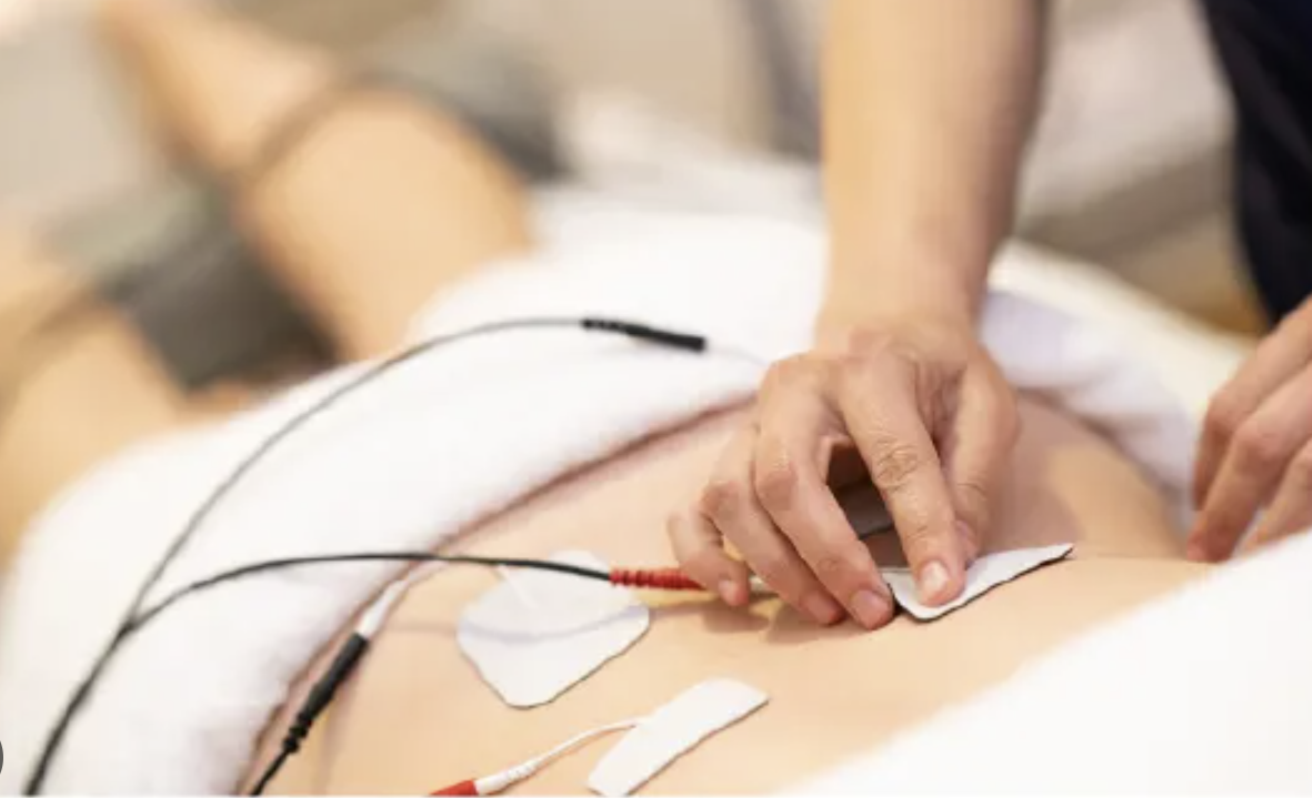 Colocación de electrodos de electroterapia en la zona lumbar de un paciente