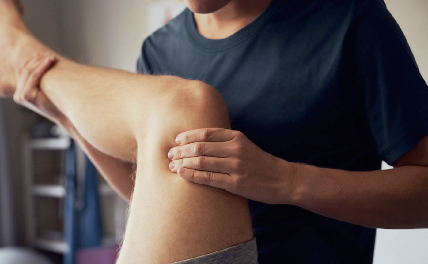 Terapia manual sobre la rodilla de un paciente en la camilla
