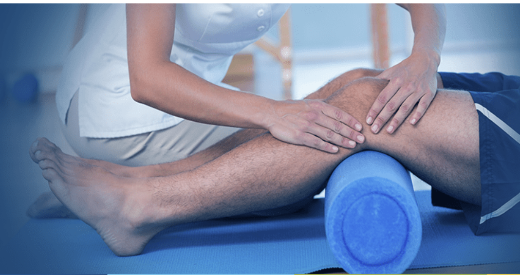 Fisioterapeuta trabajando la musculatura de la pierna de un paciente con un rodillo de espuma