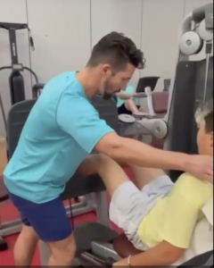 Fisioterapeuta movilizando la rodilla de un paciente joven tumbado en la camilla de la sala