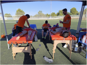 Atención fisioterapéutica a jugadores sobre camillas a pie de campo de fútbol