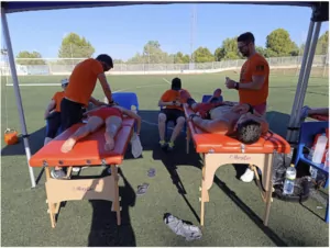 Atención fisioterapéutica a jugadores sobre camillas a pie de campo de fútbol