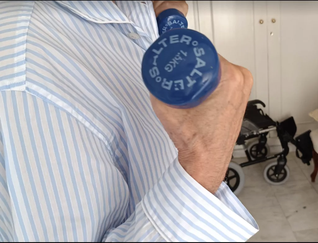 Persona mayor levantando una mancuerna de 1,5 kg en una sesión de rehabilitación cardíaca